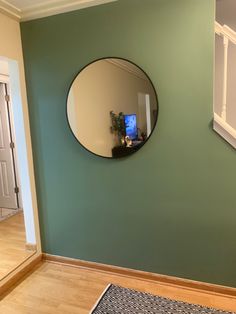 there is a mirror on the wall in this room with wood flooring and green walls