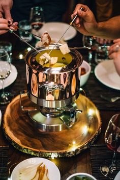 people are eating food at a table with plates and wine glasses on the table in front of them