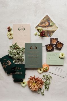 the wedding stationery is laid out on top of the table with flowers and cards