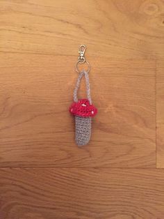 a crocheted keychain with a small red mushroom on it's side