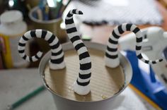 two black and white striped candles sitting in a cup on top of a table next to other office supplies