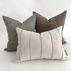 three pillows with different patterns on them sitting side by side in front of a white background