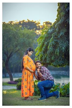 a man kneeling down next to a woman in an orange dress