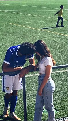 a man and woman standing next to each other on a soccer field