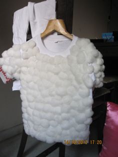 a white shirt that has been made out of cotton balls on a wooden hanger