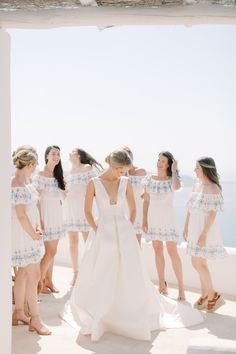 a group of women standing next to each other on top of a white building near the ocean