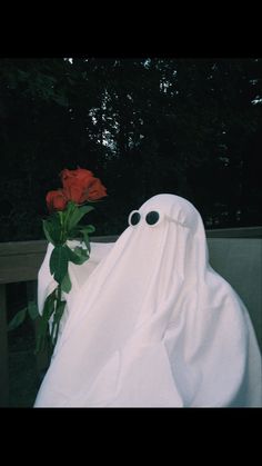 a fake ghost sitting next to a red rose