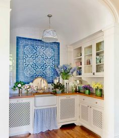 a blue and white tile backsplash in a kitchen with wooden floors, cabinets, and cupboards