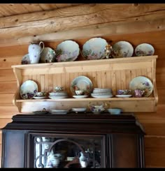 an old china cabinet with plates and cups on it