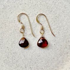 Our simple dainty garnet drop earrings are a classic pair and the perfect lightweight everyday earring. The sparkling genuine garnet gemstones are striking and make a minimalist statement. Garnet is the January birthstone. Because of their simple style, they are the perfect pair to complement a necklace. They would make a beautiful personalized gift as we offer a choice of every month's birthstone as well as other popular gemstones in the drop-down menu. Also available in gold filled, sterling silver, rose gold filled and 14k gold. The model is wearing the garnet January birthstone earrings in 14k gold filled. CRAFTSMANSHIP  Jewelry is handmade by us in our NYC studio. We focus on craftsmanship and quality using only the highest quality materials and handpicked genuine gemstones.  PACKAGIN Garnet Drop Earrings With Ear Wire, Garnet Gemstone Drop Earrings, Elegant Garnet Teardrop Earrings, Classic Dangle Faceted Earrings, Faceted Garnet Drop Earrings, Garnet Faceted Drop Earrings, Classic Faceted Dangle Earrings, Elegant Garnet Briolette Earrings, Elegant Briolette Garnet Earrings