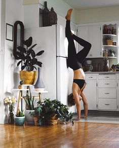 a woman is doing a handstand in the kitchen