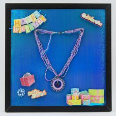 a birthday gift is displayed in a shadow box with beads and other items around it