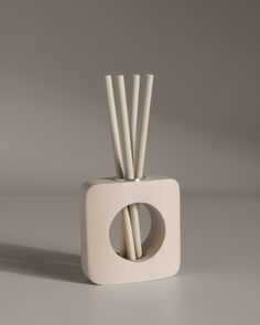 a white vase with some sticks sticking out of it