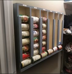 an organized spice rack in the corner of a room with spices and cans on it