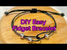 the diy easy fidget bracelet is made with black string and silver beads on a wooden