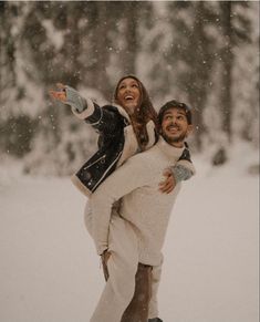 a man carrying a woman on his back while they are snowing in the woods