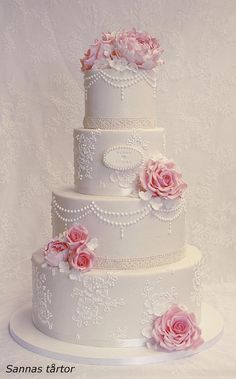 a three tiered wedding cake with pink flowers on the side and pearls around the edges