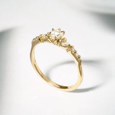 a yellow gold ring with three stones on the top and bottom, sitting on a white surface