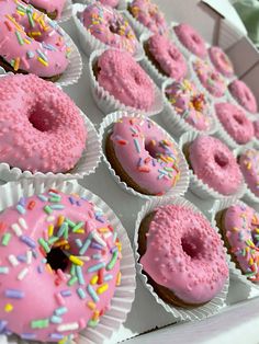 pink frosted doughnuts with sprinkles are displayed in white boxes