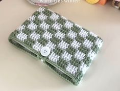 a green and white crochet purse sitting on top of a table next to a plate