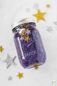 a mason jar filled with purple and gold stars