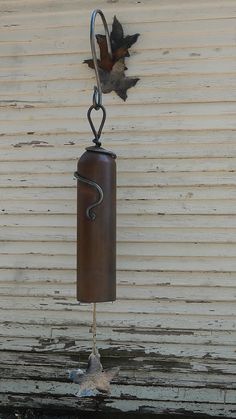 a wind chime hanging from the side of a building with leaves attached to it