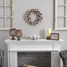 a living room with a fireplace, chair and wreath on the mantle