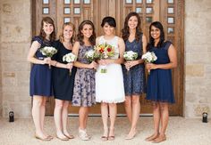 a group of women standing next to each other in front of a door holding bouquets