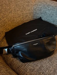 This sleek and stylish Saint Laurent leather belt bag is the perfect accessory for any fashion-forward individual. Made from high-quality leather, this bag is both durable and chic. It features a black exterior with silver hardware, as well as a black lining and handle/strap. With its unisex design, this bag is suitable for both men and women, and its versatile style makes it the perfect addition to any outfit. Whether you're hitting the town or running errands, this belt bag will keep your essentials close at hand. This bag is in excellent condition. My husband only wore it a handful of times and just decided it wasn’t for him. Leather Belt Bag, Black Exterior, Versatile Style, Silver Hardware, High Quality Leather, Unisex Design, Belt Bag, My Husband, Running Errands