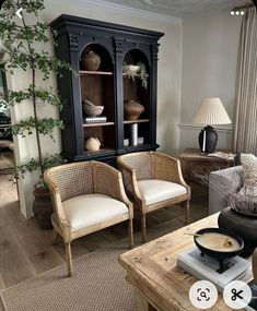 a living room with two chairs and a bookcase in the corner, next to a coffee table