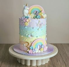 there is a cake decorated with unicorns and rainbows on the top, as well as flowers