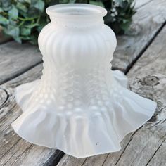 a white glass vase sitting on top of a wooden table