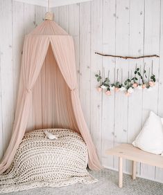 a bed with a pink canopy over it in a room next to a wooden wall