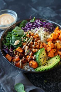 a salad with carrots, avocado, and other vegetables in a bowl