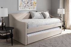 a day bed with pull out trundle in a living room next to a lamp