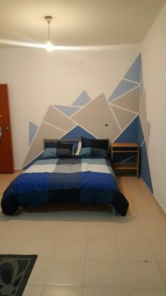 a bed with blue and white sheets in a bedroom next to a wall painting on the wall