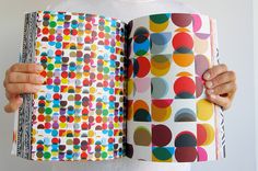 a person holding an open book with colorful circles printed on it and the cover opened