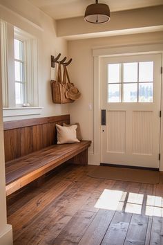 a wooden bench sitting in front of a door on top of a hard wood floor