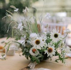 the table is set with white flowers and greenery