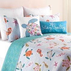 a bed covered in pillows and blankets with sea turtles on them, along with the words stay salty