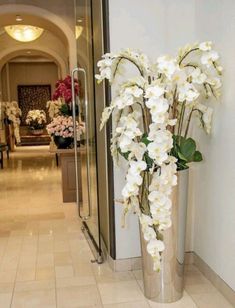 a vase with white flowers in it sitting on the floor next to a door way