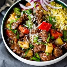 a white bowl filled with meat and veggies on top of a blue cloth