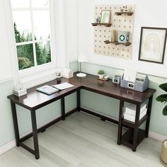 a corner desk in the corner of a room with a plant and pictures on the wall