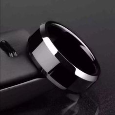 a black and white wedding ring sitting on top of a leather seat next to a knife