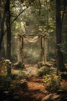 a path in the middle of a forest with an arch decorated with flowers and greenery