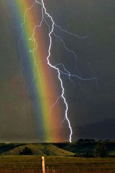 a rainbow appears to be in the middle of a storm with lightning coming from behind it