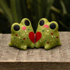 two green frog figurines with hearts on their backs