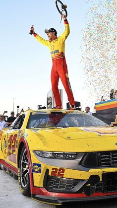 a man standing on top of a yellow race car