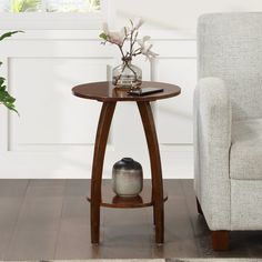 a small table with a vase on it next to a chair