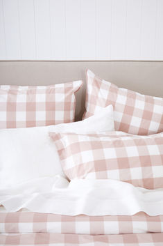 an unmade bed with pink and white checkered sheets